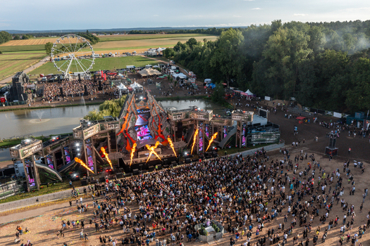 Herzogenaurach Germany 27 July 2025 Aerial view of the Open Beatz Festival featuring a large main stage with fire effects a dense crowd and a ferris wheel in the background. Herzogenaurach Germany 27 July 2025 Aerial view of the Open Beatz Festival featuring a large main stage with fire effects a dense crowd and a ferris wheel in the background.