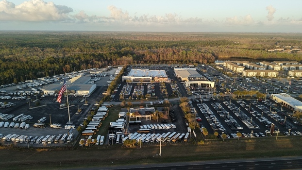 Aerial view of a sprawling RV dealership with neat rows of white vehicles contrasting against the backdrop of dense green forest under a soft diffused sunlight St. Augustine Florida United States. Aerial view of a sprawling RV dealership with neat rows of white vehicles contrasting against the backdrop of dense green forest under a soft diffused sunlight St. Augustine Florida United States.