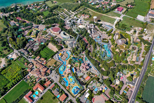 Aerial view of Gardaland Park featuring roller coasters water attractions and lush green trees near the shores of Lake Garda in Ronchi Veneto Italy. Aerial view of Gardaland Park featuring roller coasters water attractions and lush green trees near the shores of Lake Garda in Ronchi Veneto Italy.