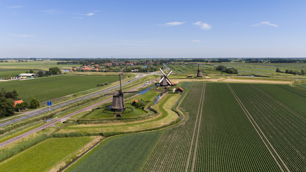 Aerial view of Bovenmolen G and surrounding historic windmills set amidst lush green agricultural fields and canals in Schermerhorn Noord Holland Netherlands. Aerial view of Bovenmolen G and surrounding historic windmills set amidst lush green agricultural fields and canals in Schermerhorn Noord Holland Netherlands.