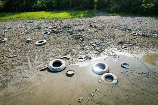 Aerial view of discarded tires and debris scattered across a parched cracked riverbed during a severe drought Carignano Piemonte Italy. Aerial view of discarded tires and debris scattered across a parched cracked riverbed during a severe drought Carignano Piemonte Italy.