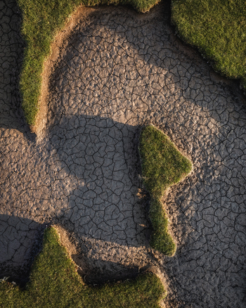 Aerial view of the intricate patterns of cracked dry earth bordered by vibrant green grass at Portmarnock Beach County Dublin Ireland. Aerial view of the intricate patterns of cracked dry earth bordered by vibrant green grass at Portmarnock Beach County Dublin Ireland.
