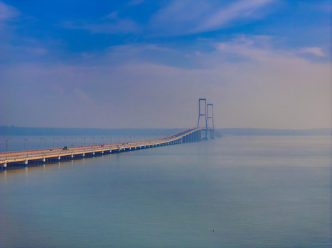 Aerial view of the Suramadu Bridge stretching across the calm sea under a clear blue sky in Kecamatan Kenjeran Jawa Timur Indonesia.