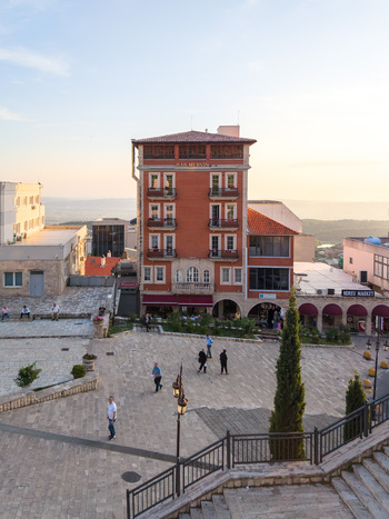 Kruje Albania 12 June 2026 Aerial view of the historic town square with a red building people walking on stone pavement and distant hills under a clear sky.