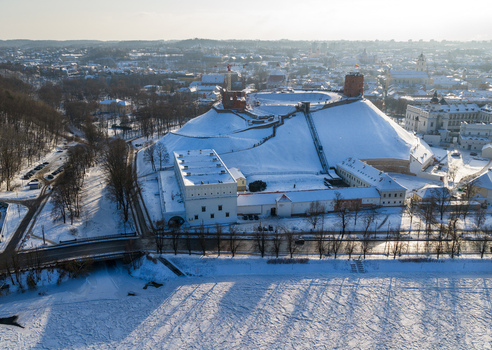 Aerial view of Gediminas Tower on a snow covered hill overlooking the frozen Neris River and historic buildings in Vilnius County Lithuania.