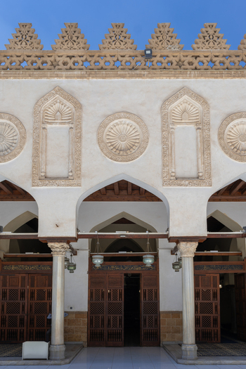 View of Al Azhar Mosque featuring intricate stone carvings arched entrances and marble columns under a clear blue sky in Cairo Egypt. View of Al Azhar Mosque featuring intricate stone carvings arched entrances and marble columns under a clear blue sky in Cairo Egypt.