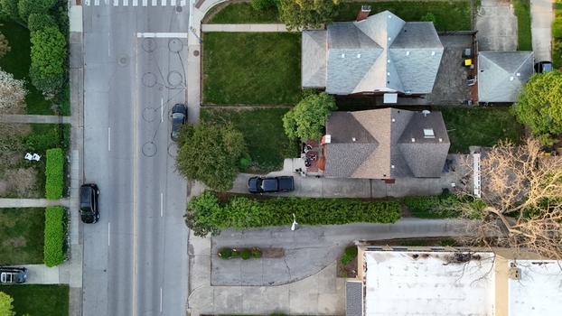 Aerial view of residential houses with grey shingle roofs green lawns and a quiet street with a crosswalk in a suburban neighborhood in Chicago Illinois United States.