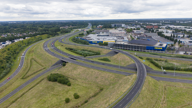 Aerial view of the IKEA store at Ekkersrijt 4089 featuring a parking structure and a highway interchange surrounded by green fields and trees in Son Noord Brabant Netherlands.