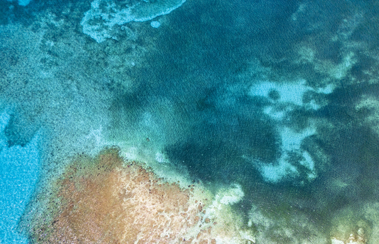 Aerial view of the crystal clear turquoise waters and vibrant coral reef formations along the coast of Guanaja island Guanaja Bay Islands Department Honduras. Aerial view of the crystal clear turquoise waters and vibrant coral reef formations along the coast of Guanaja island Guanaja Bay Islands Department Honduras.