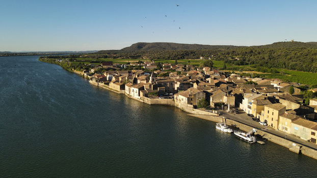 Aerial view of the historic riverside village featuring stone houses a church steeple and boats moored along the riverbank in Saint Etienne des Sorts Occitanie France. Aerial view of the historic riverside village featuring stone houses a church steeple and boats moored along the riverbank in Saint Etienne des Sorts Occitanie France.