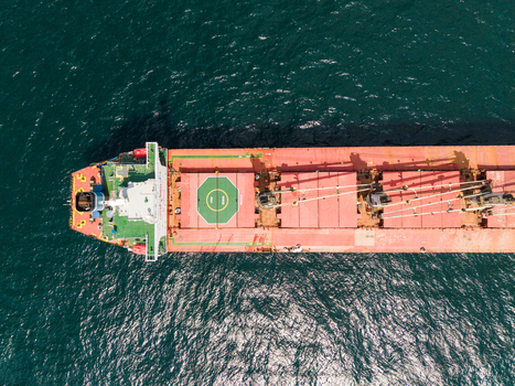 Aerial view of a large bulk carrier cargo ship with a red deck and green helipad navigating the deep blue waters of the Black Sea near Varna Varna Bulgaria. Aerial view of a large bulk carrier cargo ship with a red deck and green helipad navigating the deep blue waters of the Black Sea near Varna Varna Bulgaria.