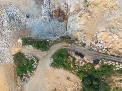 Aerial view of a mining site with a dirt road a truck rocky terrain and surrounding vegetation in Bukit Tambun Penang Malaysia. Aerial view of a mining site with a dirt road a truck rocky terrain and surrounding vegetation in Bukit Tambun Penang Malaysia.
