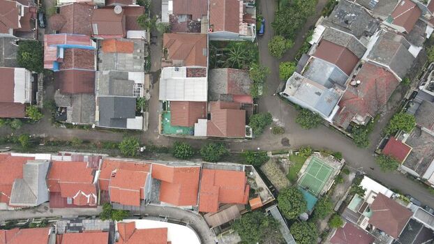 Aerial view of a dense residential neighborhood with red tiled rooftops narrow streets and a small tennis court in Depok West Java Indonesia. Aerial view of a dense residential neighborhood with red tiled rooftops narrow streets and a small tennis court in Depok West Java Indonesia.