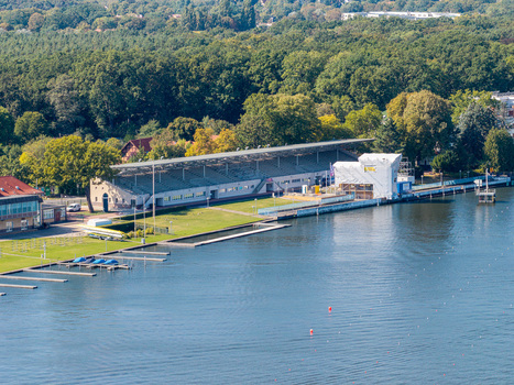 Aerial view of the historic Regattatribune Berlin Grunau grandstand situated along the Dahme river with lush surrounding trees and rowing docks in Berlin Berlin Germany. Aerial view of the historic Regattatribune Berlin Grunau grandstand situated along the Dahme river with lush surrounding trees and rowing docks in Berlin Berlin Germany.