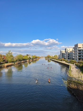 Hannover Germany 14 April 2026 View of kayakers paddling on the calm waters of the canal near Holzwiesen with modern apartment buildings along the bank under a clear blue sky.