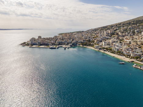 Aerial view of the coastal city of Saranda with its harbor buildings and beach along the Ionian Sea in Saranda Vlore County Albania. Aerial view of the coastal city of Saranda with its harbor buildings and beach along the Ionian Sea in Saranda Vlore County Albania.