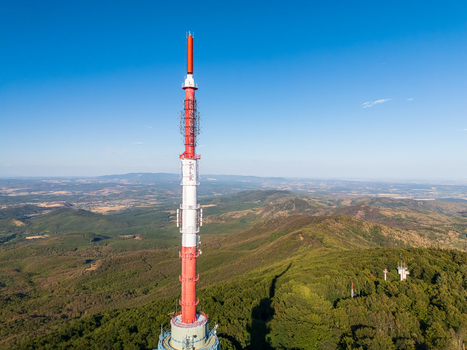 Aerial view of Kekes TV Tower and observation tower in the Matra Mountains Hungary above forested slopes under blue summer sky with broadcasting and telecommunication infrastructure Aerial view of Kekes TV Tower and observation tower in the Matra Mountains Hungary above forested slopes under blue summer sky with broadcasting and telecommunication infrastructure