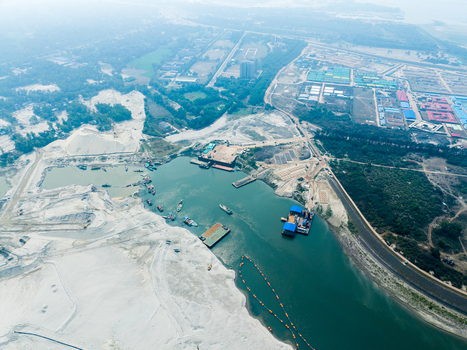 Aerial view of industrial sand extraction operations along the river with barges and sand piles in Tangail Dhaka Division Bangladesh. Aerial view of industrial sand extraction operations along the river with barges and sand piles in Tangail Dhaka Division Bangladesh.