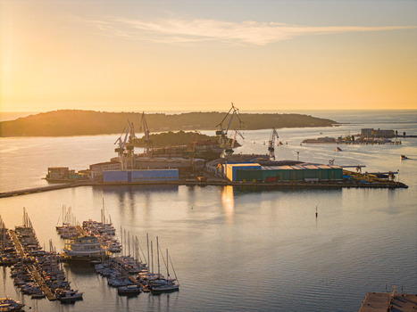 Aerial view of the shipyard basks in the golden light of dawn contrasting with the calm deep blue waters surrounding it Pula Istria County Croatia.