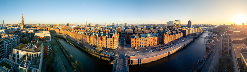 Aerial view of the Speicherstadt district with historic red brick warehouses and canals under a golden sunset sky in Hamburg Hamburg Germany. Aerial view of the Speicherstadt district with historic red brick warehouses and canals under a golden sunset sky in Hamburg Hamburg Germany.
