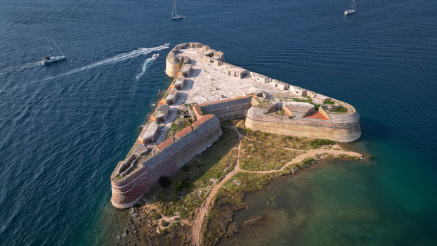 Aerial view of the triangular St. Nicholas Fortress surrounded by the blue Adriatic Sea with boats sailing nearby in Sibenik Croatia.
