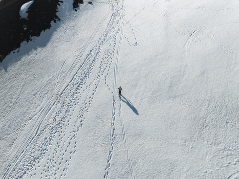 Aerial view of a lone skier crossing the snowy slopes of the south side of Mount Etna with numerous tracks and long shadows Nicolosi Sicilia Italy. Aerial view of a lone skier crossing the snowy slopes of the south side of Mount Etna with numerous tracks and long shadows Nicolosi Sicilia Italy.