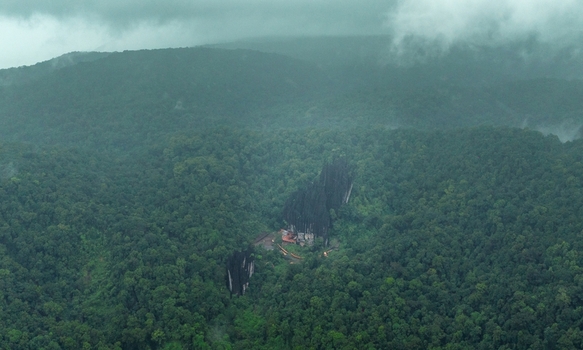 Aerial view of the unique karst rock formations of Yana Caves surrounded by dense lush green forest under a cloudy sky in Yana Karnataka India.