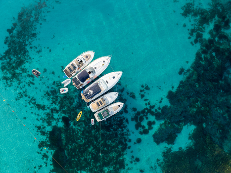 Aerial view of luxury yachts resting on the turquoise waters of the Blue Lagoon a vibrant contrast to the dark reef below Comino Malta. Aerial view of luxury yachts resting on the turquoise waters of the Blue Lagoon a vibrant contrast to the dark reef below Comino Malta.