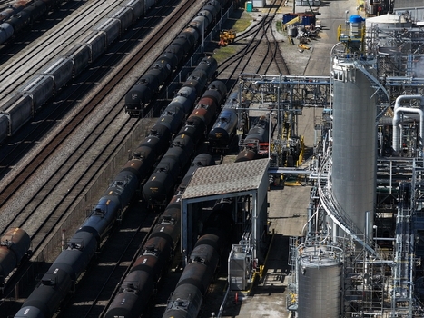 Aerial view of black tank cars on railway tracks at an industrial refinery facility with storage tanks and complex piping in Cincinnati OH United States. Aerial view of black tank cars on railway tracks at an industrial refinery facility with storage tanks and complex piping in Cincinnati OH United States.