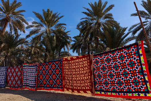 View of traditional colorful Ralli quilts hanging on a line in a palm grove in Nagarparkar Sindh Pakistan.
