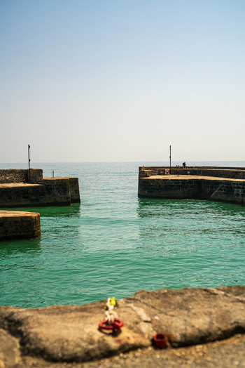 View of the historic stone harbor walls and calm turquoise water at Charlestown Cornwall United Kingdom. View of the historic stone harbor walls and calm turquoise water at Charlestown Cornwall United Kingdom.