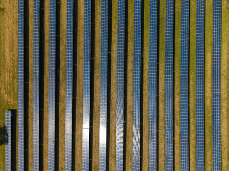 Aerial view of Lisburn Solar Farm with long rows of photovoltaic panels arranged in parallel lines across a grassy field in Lisburn Northern Ireland United Kingdom. Aerial view of Lisburn Solar Farm with long rows of photovoltaic panels arranged in parallel lines across a grassy field in Lisburn Northern Ireland United Kingdom.