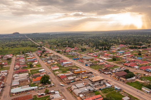 Aerial view of Katakwi Town Council featuring a grid of buildings paved roads and surrounding lush green landscape under a dramatic cloudy sky in Katakwi Eastern Region Uganda. Aerial view of Katakwi Town Council featuring a grid of buildings paved roads and surrounding lush green landscape under a dramatic cloudy sky in Katakwi Eastern Region Uganda.