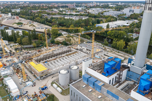 Aerial view of the Klarwerk Ruhleben sewage treatment plant under construction with large industrial tanks cranes and surrounding greenery in Berlin Berlin Germany.