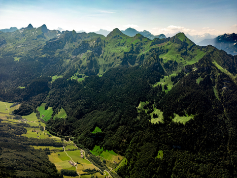 Aerial view of verdant mountains blanketed by dense forests with pockets of bright green meadows nestled in the valleys Morschach Schwyz Switzerland. Aerial view of verdant mountains blanketed by dense forests with pockets of bright green meadows nestled in the valleys Morschach Schwyz Switzerland.