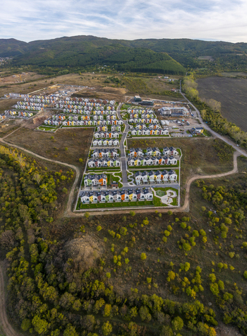 Aerial view of Residential Park Lozen featuring rows of modern colorful houses with green lawns and paved streets surrounded by autumn hills in Sofia Sofia City Province Bulgaria. Aerial view of Residential Park Lozen featuring rows of modern colorful houses with green lawns and paved streets surrounded by autumn hills in Sofia Sofia City Province Bulgaria.