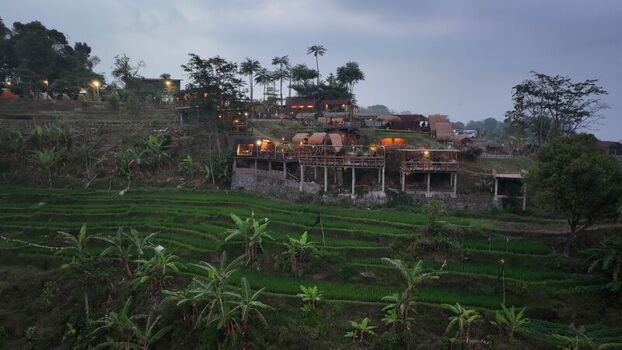 Aerial view of a hillside resort overlooking lush green terraced rice fields in Trawas East Java Indonesia. Aerial view of a hillside resort overlooking lush green terraced rice fields in Trawas East Java Indonesia.