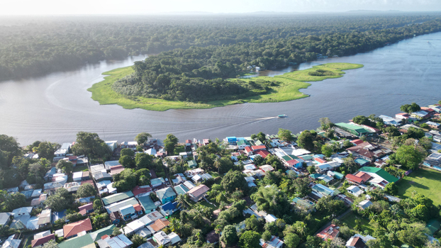 Aerial view of the river snaking through the lush green jungle where homes with vibrant roofs cluster near the water s edge Tortuguero Limón Province Costa Rica. Aerial view of the river snaking through the lush green jungle where homes with vibrant roofs cluster near the water s edge Tortuguero Limón Province Costa Rica.