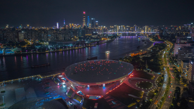 Aerial view of the saucer shaped Mercedes Benz Arena illuminated with colorful lights at night by the Huangpu River in Shanghai Shanghai China.