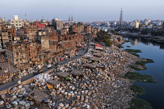 Aerial view of the Buriganga River with dense urban buildings and large piles of collected waste along the riverbank Dhaka Dhaka Division Bangladesh. Aerial view of the Buriganga River with dense urban buildings and large piles of collected waste along the riverbank Dhaka Dhaka Division Bangladesh.
