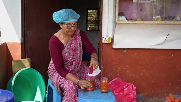 View of a woman sealing food jars with an iron in Dhangadhi Nepal. View of a woman sealing food jars with an iron in Dhangadhi Nepal.