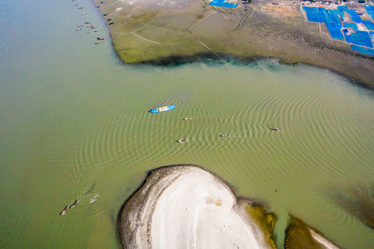 Aerial view of Kuakata beach with small fishing boats navigating the river sandy banks and coastal landscape in Kuakata Barisal Division Bangladesh. Aerial view of Kuakata beach with small fishing boats navigating the river sandy banks and coastal landscape in Kuakata Barisal Division Bangladesh.