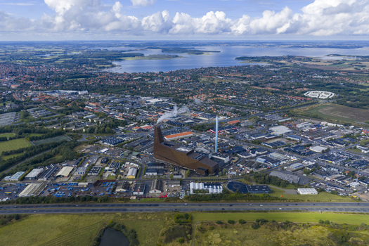 Aerial view of the modern Energitarnet waste to energy plant with its distinctive brown facade and chimney overlooking the urban landscape and fjord in Roskilde Denmark. Aerial view of the modern Energitarnet waste to energy plant with its distinctive brown facade and chimney overlooking the urban landscape and fjord in Roskilde Denmark.