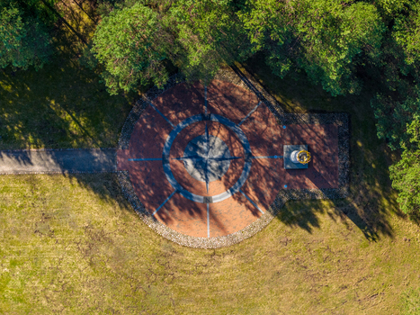 Aerial view of The Geographical Centre Of Europe monument featuring a large compass rose design surrounded by lush green trees in Girija Vilnius County Lithuania. Aerial view of The Geographical Centre Of Europe monument featuring a large compass rose design surrounded by lush green trees in Girija Vilnius County Lithuania.