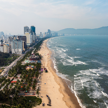 Aerial view of the coastline of Da Nang with modern high rise buildings sandy beach palm trees and waves rolling onto the shore Vietnam. Aerial view of the coastline of Da Nang with modern high rise buildings sandy beach palm trees and waves rolling onto the shore Vietnam.