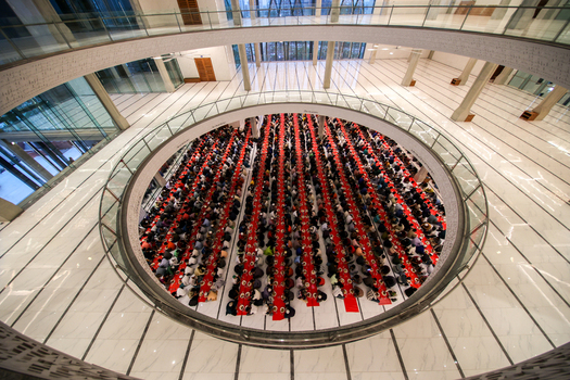 Dhaka Bangladesh 19 March 2025 View of a large corporate event in a circular atrium vibrant red tables packed with dark suited attendees under modern architecture. Dhaka Bangladesh 19 March 2025 View of a large corporate event in a circular atrium vibrant red tables packed with dark suited attendees under modern architecture.