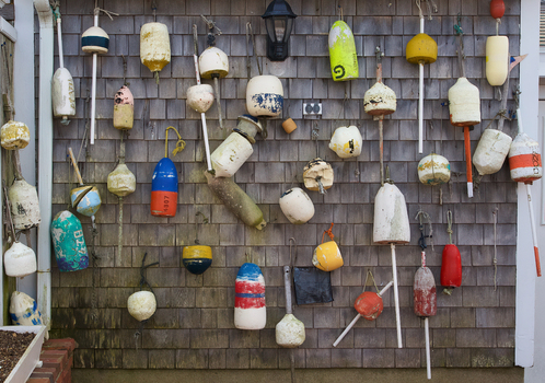 View of numerous colorful and weathered fishing buoys hanging on a grey wooden shingle wall of a coastal building in Martha s Vineyard Massachusetts