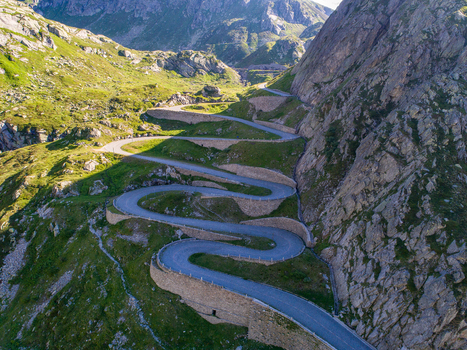 View of the winding Tremola road at Sankt Gotthard Pass with hairpin turns on a steep mountain slope under bright sunlight Airolo Ticino Switzerland.
