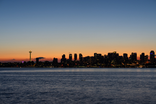 View of the Seattle skyline at sunset with the Space Needle silhouette against the colorful evening sky across the water in Seattle Washington United States. View of the Seattle skyline at sunset with the Space Needle silhouette against the colorful evening sky across the water in Seattle Washington United States.