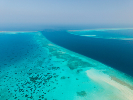 Aerial view of the turquoise waters embracing the pristine sandbanks and deep blue channels Vashafaru Island Thiladhummathi Atoll Maldives.